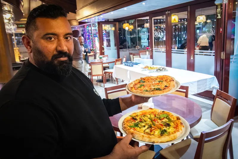 Gill's chef holding two freshly made pizzas